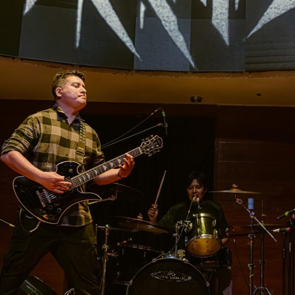 Sickness tocando la guitarra junto a la batería en un concierto de Kraimz